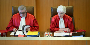 Verfassungsrichter Peter Müller und Doris König sitzen in roten Roben am Richtertisch