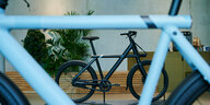 Blick durch einen hellblauen Fahrradrahmen auf ein schwarzes E-Bike