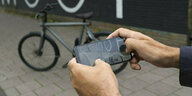 Männerhände an einem Handy machen ein Foto vom VanMoof Fahrrad