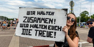 Ein weiblicher Rammmstein-Fan hält ein Schild in die Kamera. Darauf steht: "Wir halten zusammen" Wir halten euch die Treue!"