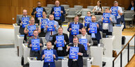 Mitglieder der AfD-Landtagsfraktion halten sich im Plenarsaal Schilder mit der Aufschrift "Keine Heizung ist illegal" vor die Brust.