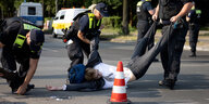 Polizisten ziehen einen Dmeonstranten im Anzug von der Straße