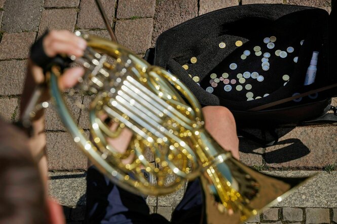 Geld im Instrumentenkasten eines Straßenmusikers, der auf einem Horn bläst