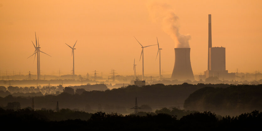 Wasserdampf steigt aus einem Kühlturm neben einem kraftwer, Widnräder im Sonnenaufgang