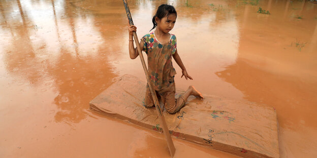 Ein Mädchen auf einer Floß im schlammigen Wasser.