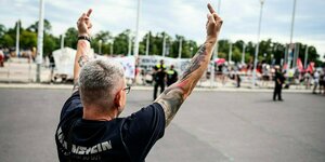 Ein Mann im Rammstein-Shirt zeigt einer Demonstration mit Kritikerinnen der Band beide Mittelfinger