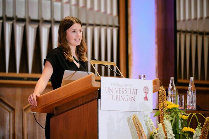 Luisa Neubauer steht in einem holvertäfelten Raum der Universität in Tübingen am Rednerpult