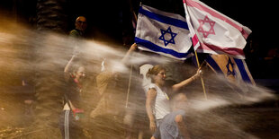 Demonstranten stehen auf dem Bürgersteig mit israelischen Flaggen.