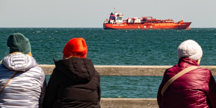 Tankschiff auf dem Meer, im Vordergrund Menschen.