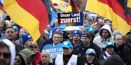Demonstrant mit Plakat Unser Land Zuerst und Deutschlandfhne auf einer Kundgebung und Demonstration der rechtsextremen Partei AfD unter dem Motto Unser Land Zuerst
