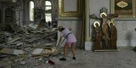 Junge Frau räumt in der beschossenen Kathedrale auf