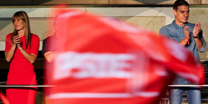 Pedro Sánchez und seine Frau mit einer PSOE-Flagge zwischen ihnen