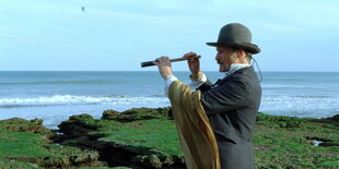 Fotostill, Viggo Mortensen schaut mit einem Fernrohr in die Landschaft