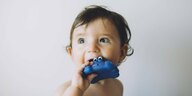 Ein Kleinkind mit Plastikspielzeug im Mund.