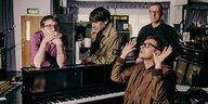 die britische Band Blur sitzt um ein Klavier