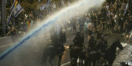 Strahl eines Wasserwerfers über iener protestierenden Menschenmenge