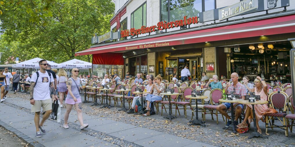 Passanten gehen an einem Cafe vorbei