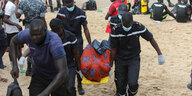 Menschen transportieren an Strand einen leblosen eingewickelten Körper