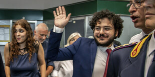 Ein Mann kommt umringt von anderen Menschen am Flughafen an