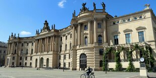 Ein Fahrradfahrer fährt am Unigebäude vorbei