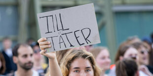 Eine Person hält bei einer Demonstration ein Schild hoch.