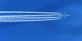 Flugzeug mit Kondensstreifen am blauen Himmel