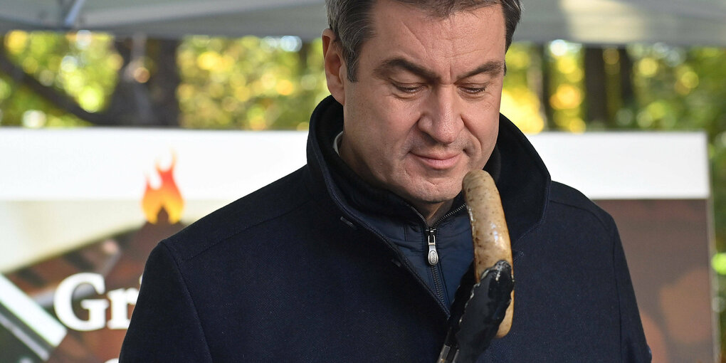 Markus Söder mit einer Bratwurst in der Hand.