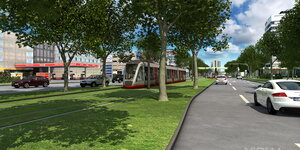 Eine rote Straßenbahn fährt auf einem Grünstreifen zwischen zwei Fahrbahnen für Autos.