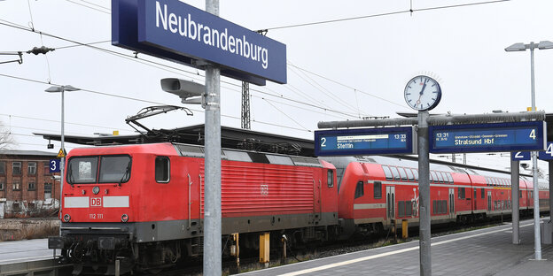 Bahnsteig im Bahnhof von Neubrandenburg. Auf einem Gleis steht eine Lok mit Waggons