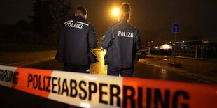 Zwei Polizisten hinter einem Absperrband