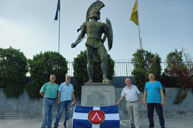 Vier Männer stehen vor einem Denkmal