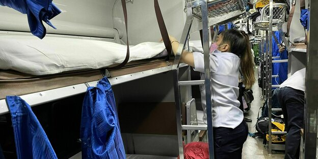 Innenansicht eines thailändischen Nachtzug, eine Angestellte der Bahnbetriebe bereitet das Bett vor