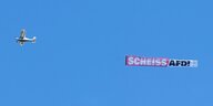 Ein Flugzeug zieht fliegend ein Banner mit der Aufschrift ·Scheiss AfD" hinter sich her