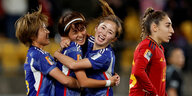 drei japanische Spielerinnen umarmen sich, eine Spanierin steht daneben