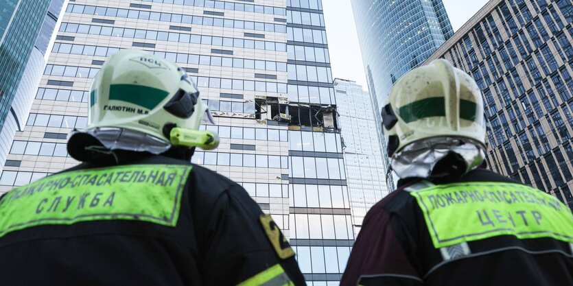 Erstversorger in der Rückansicht schauen auf ein verglastes Hochhaus