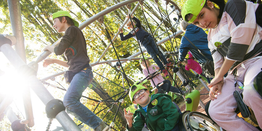 Kinder spielen auf einem Spielplatz, darunter auch zwei im Rollstuhl