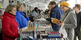 Menschen an Verkaufsständen, die Bücher anschauen oder verkaufen