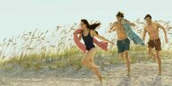 Eine junge Frau und Zwei Männer in Badebekleidung laufen über den Sand