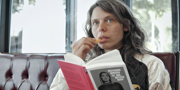 Hauptdarstellerin Margarita Breitkreiz unterbricht die Lektüre eines feministischen Buchs, um einen Kartoffelchip zu snacken, und schaut dabei angriffslustig zu ihrem Gegenüber