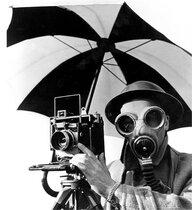 Schwarz-Weiß-Aufnahme von einem Mann mit Gasmaske, Regenschirm und Kamera aus der Zeit des Zweiten Weltkriegs