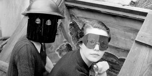 Zwei Personen mit Masken in einem historischen Foto.