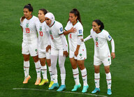 Nouhaila Benzina mit Hischab steht mit vier Mitspielerinnen in der freistoßmauer