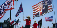Unterstützer von Donald Trump stehen mit US-Flaggen mit seinem Porträt auf der Straße