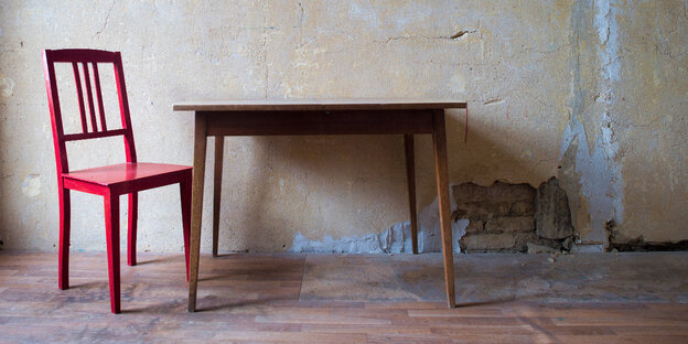 Ein roter Stuhl steht in einem Raum neben einem Tisch