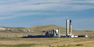 Ein Kraftwerk steht vor blauem Himmel in einer wüstenähnlichen Umgebung