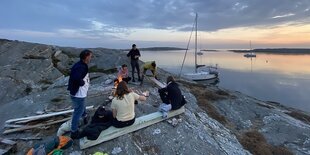 Menschen sitzen an einem Lagerfeuer am Meer