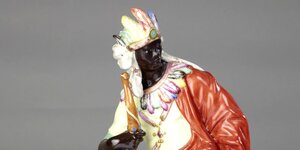 Die Porzellanfigur der Allegorie von Afrika trägt eine Federkrone