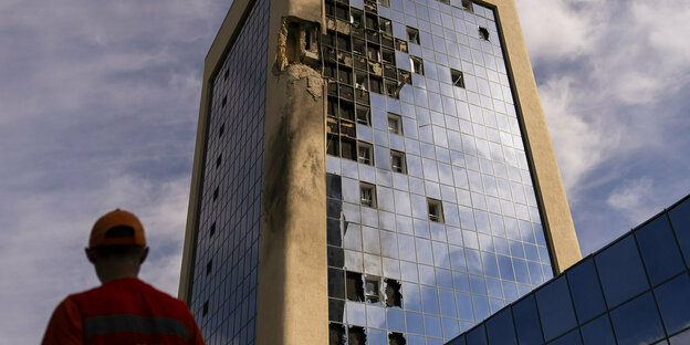 Ein Wartungsarbeiter steht nach russischen Drohnenangriffen vor einem beschädigten Regierungsgebäude