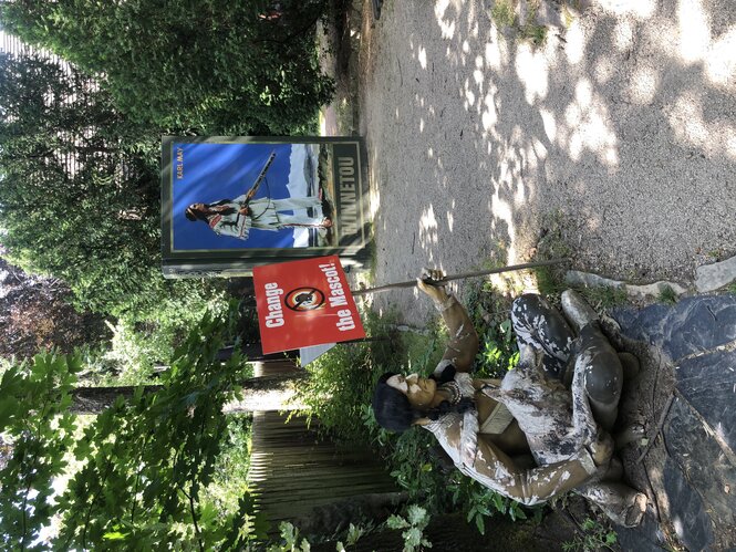 Eine Holzfigut hält ein Protestplakat