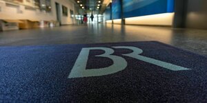 Ein weiter Flur mit blauem Teppich und den weißen Buchstaben "BR"